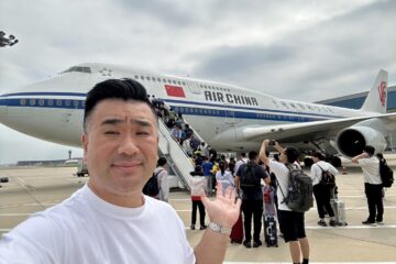 a man taking a selfie with a plane in the background