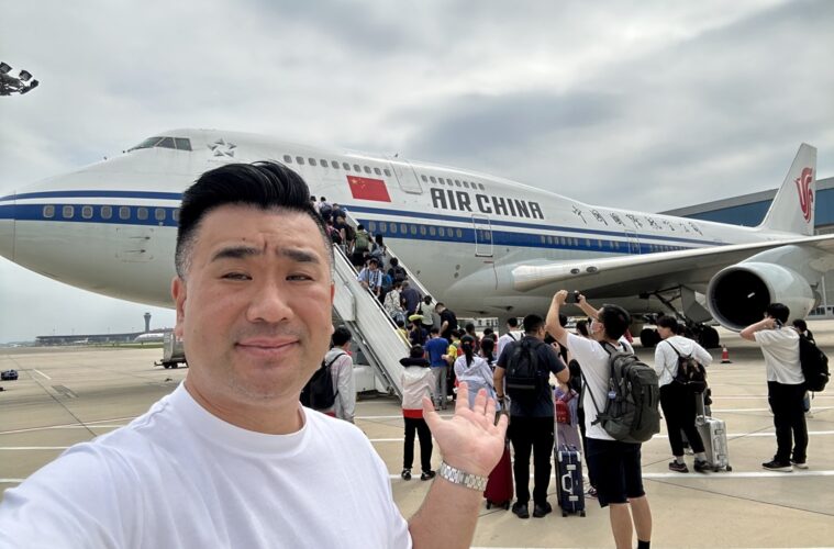 a man taking a selfie with a plane in the background