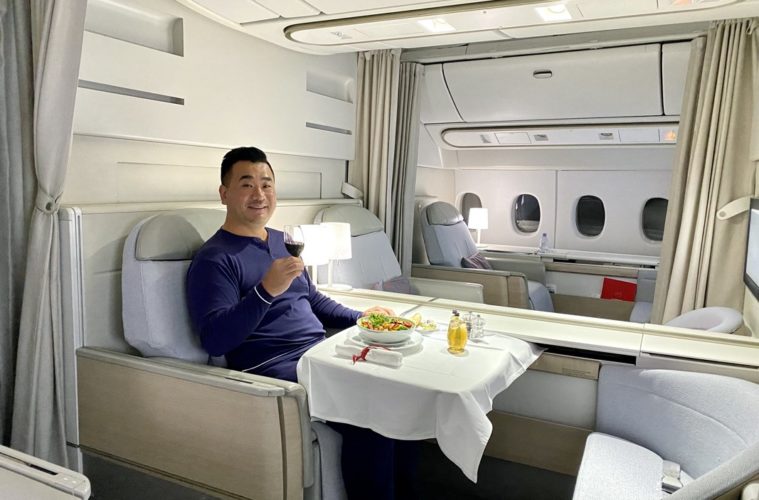 a man sitting in a chair with a plate of food and a glass of wine