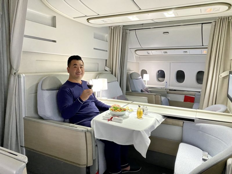 a man sitting in a chair with a plate of food and a glass of wine