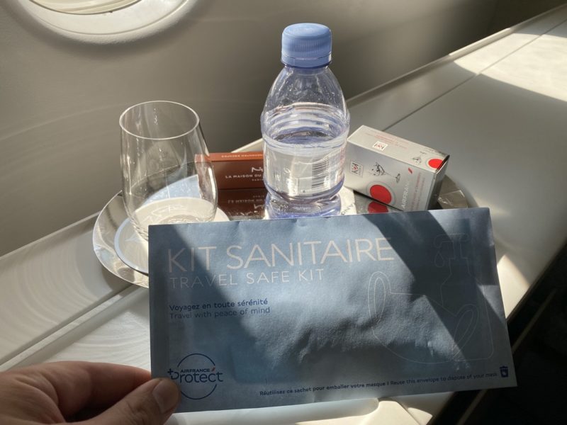 a hand holding a package and a bottle of water next to a glass