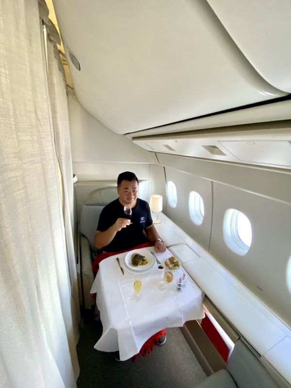 a man sitting at a table with food and a glass of wine