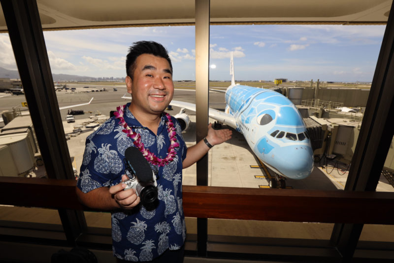 a man holding a camera and standing in front of an airplane