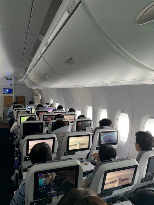 a group of people sitting in an airplane with monitors