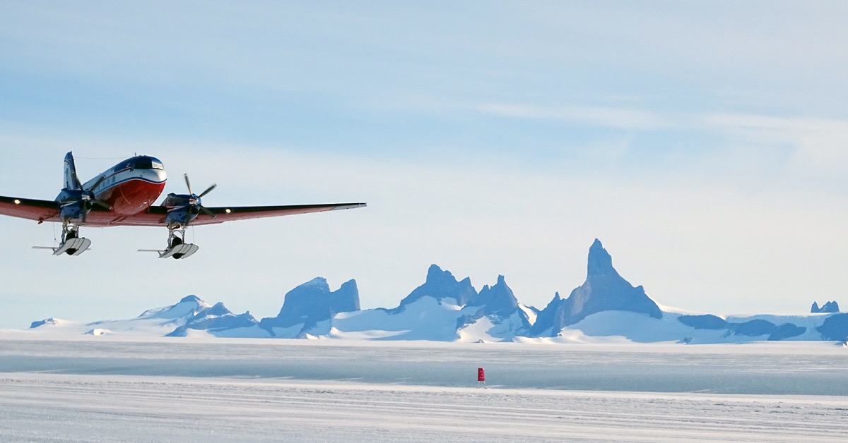 an airplane flying over a snowy landscape