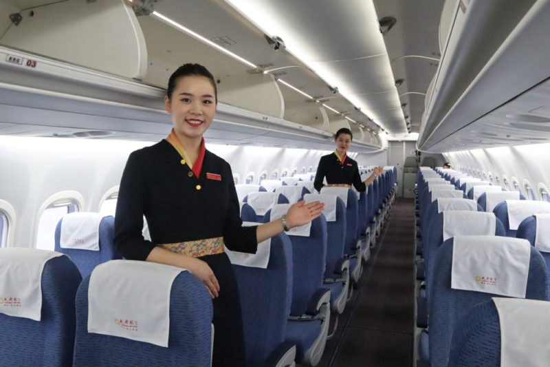 a woman in uniform standing in an airplane