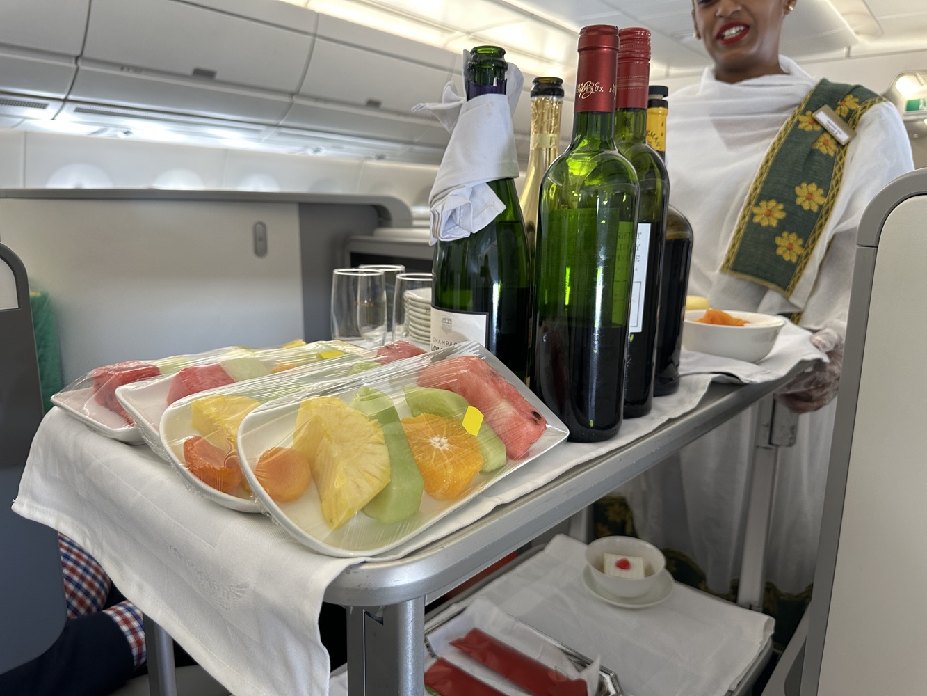 a woman standing behind a tray of food and wine