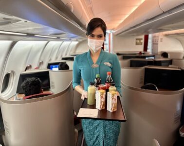 a woman wearing a mask and gloves holding a tray with drinks