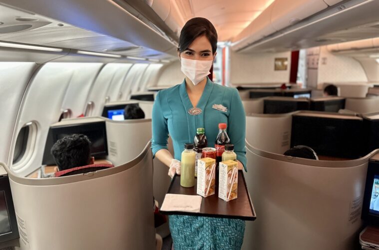 a woman wearing a mask and gloves holding a tray with drinks