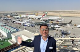 a man standing on a balcony with planes in the background