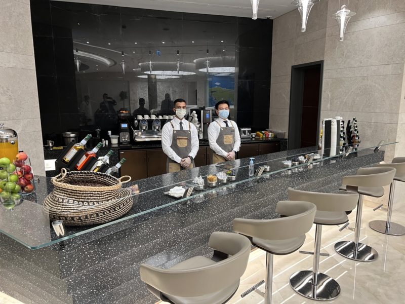 two men standing behind a counter with a face mask