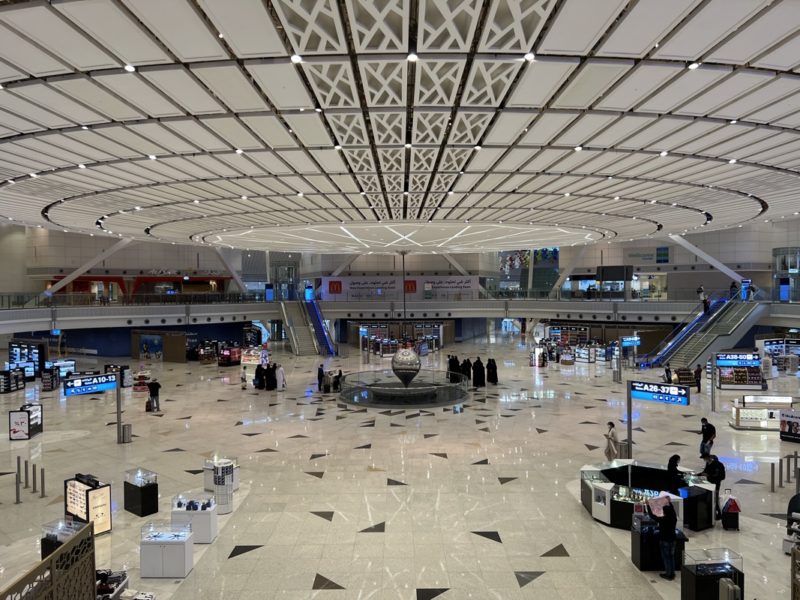 a large white and black tiled floor with people walking around