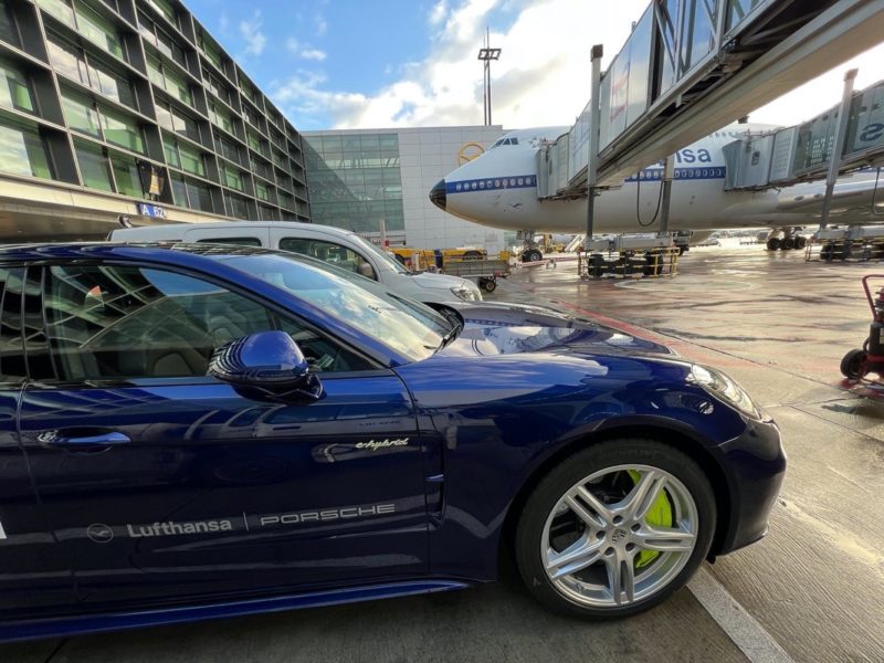 a blue car parked next to a plane