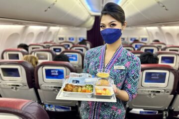 a woman wearing a face mask holding a tray of food