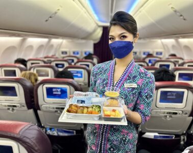 a woman wearing a face mask holding a tray of food