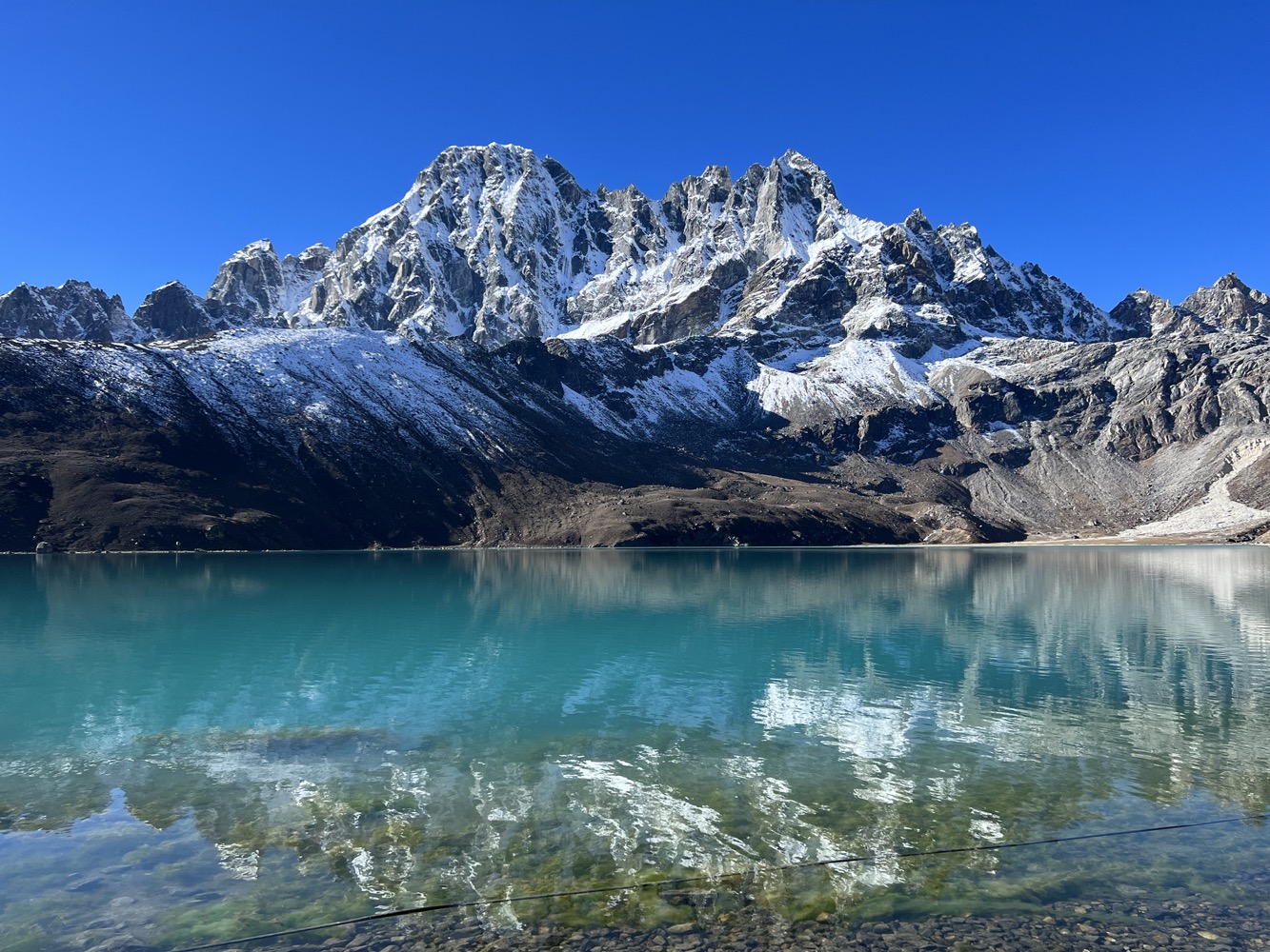 a mountain with snow on the top and a body of water