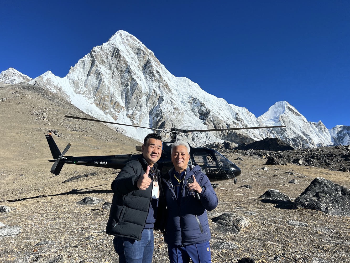 a man and woman standing in front of a helicopter