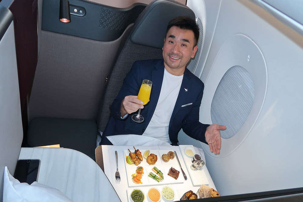 a man sitting in a chair with a glass of juice and food on the table