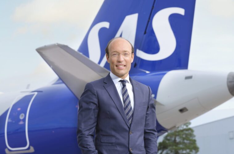 a man in a suit standing in front of a plane