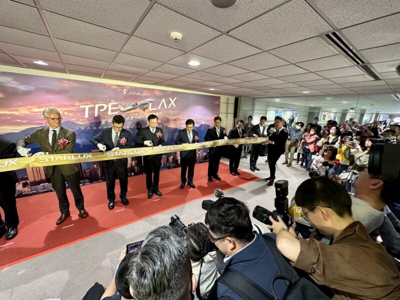 a group of people standing on a red carpet with a ribbon