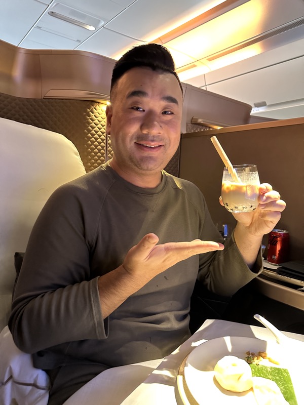 a man holding a glass with a straw and a plate of food