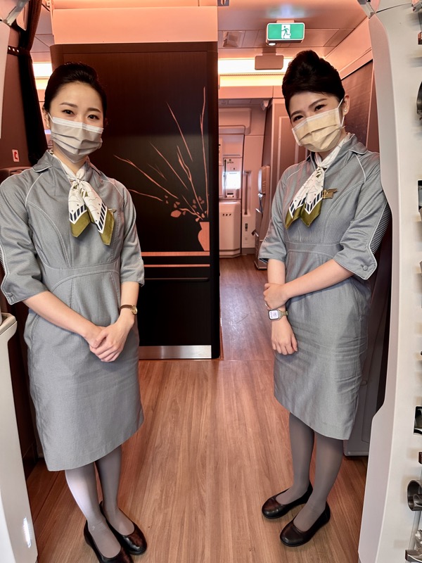 two women wearing masks and standing in a room