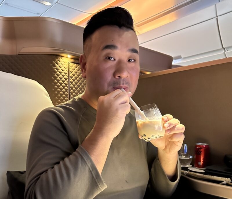 a man sitting in a chair drinking from a glass with a spoon